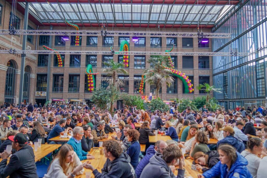 Festivaliers assis sur les tables de l'Atrium au Lille Street Food Festival 2025.